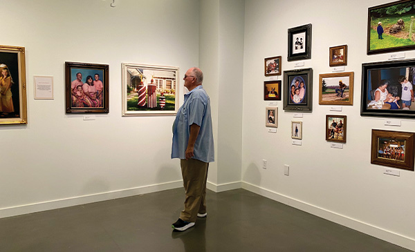 A middle-aged man looking at a gallery wall of photos in a museum