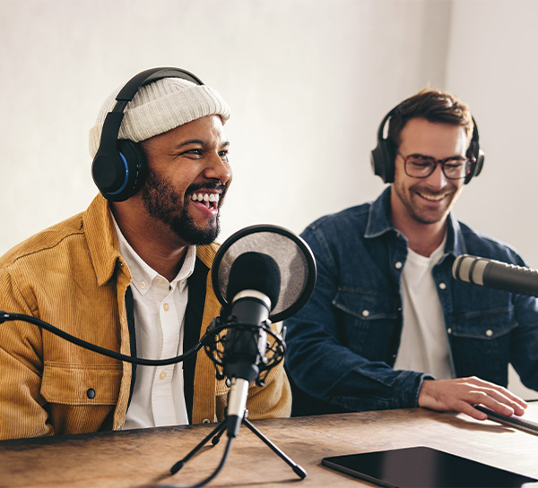 Two men recording a podcast with microphones and headphones